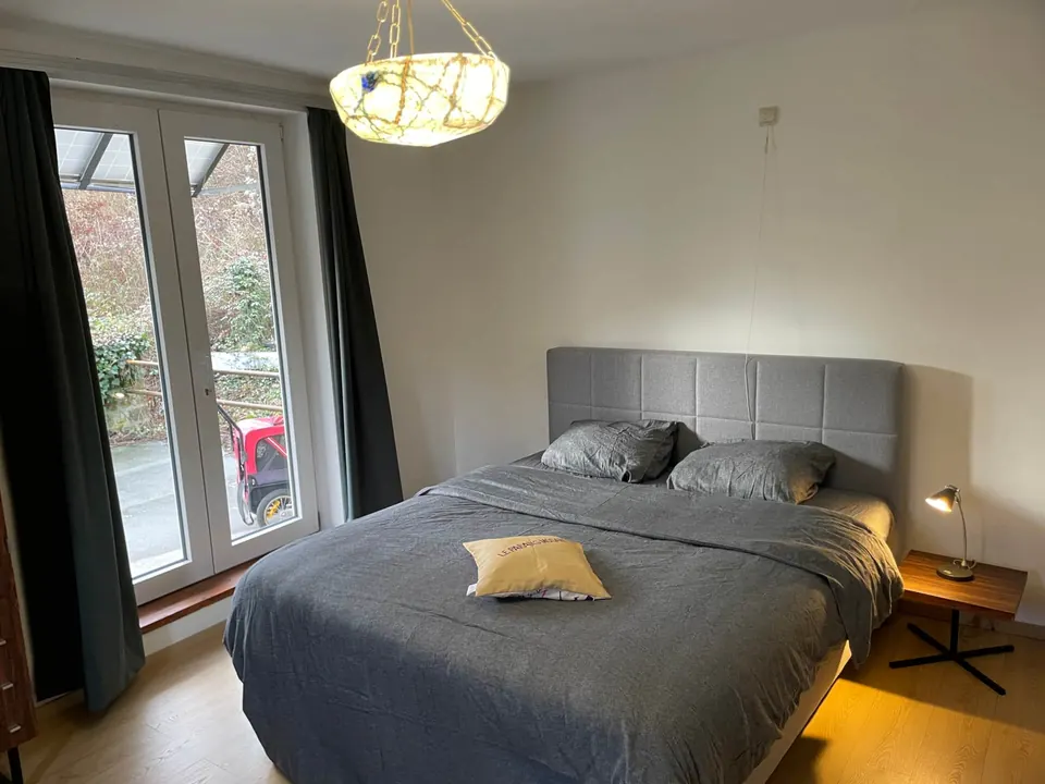 Chambre du rez-de-chaussée avec grand lit et porte-fenêtre
